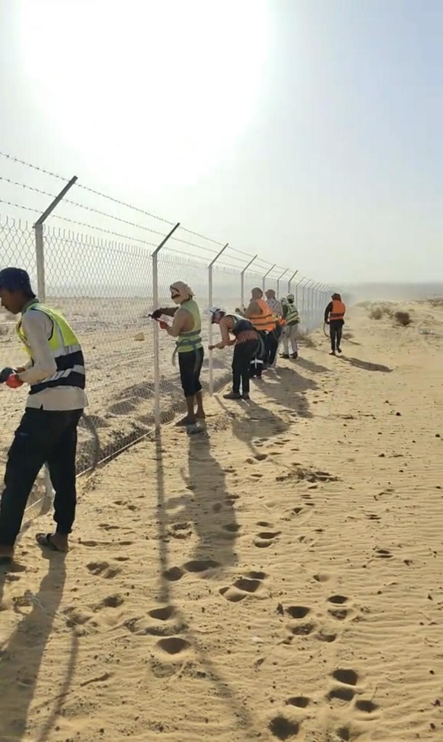 فريق عمل أثناء تركيب السياج الأمني في الصحراء